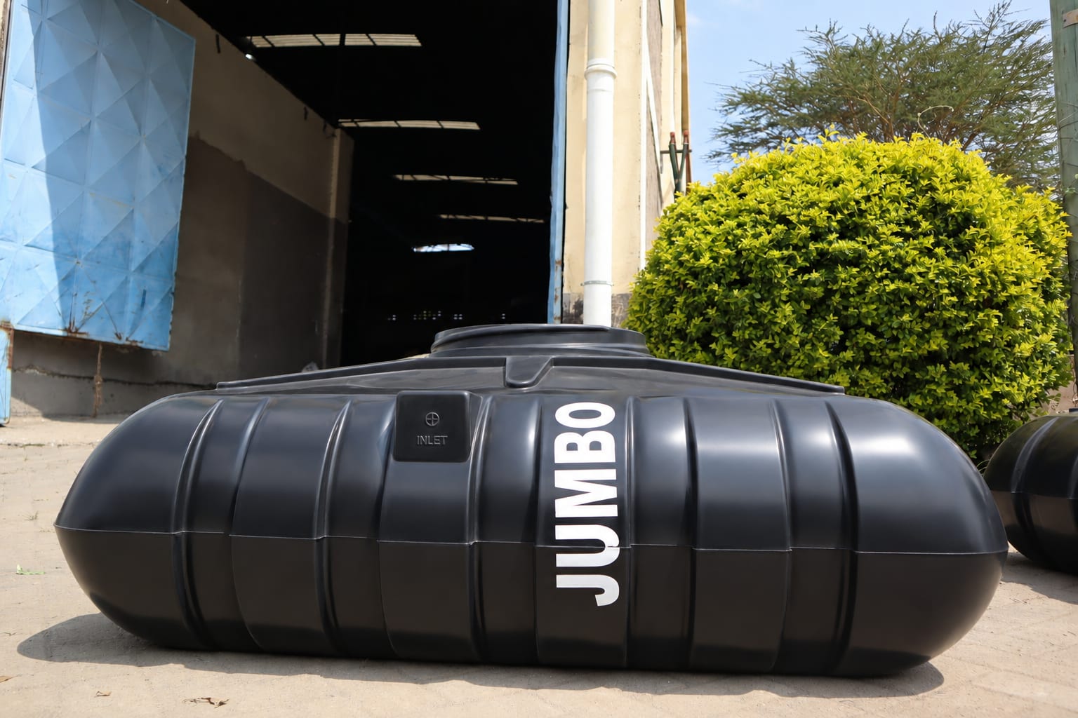 A black Jumbo horizontal tank with a moulded INLET cover and the JUMBO wordmark, outside the factory.